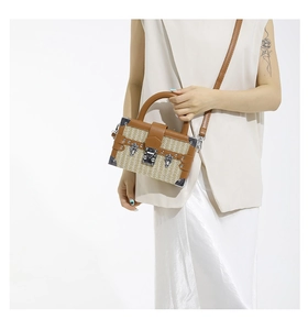 Detail of woven straw box bag featuring brown leather trim and vintage metal clasp