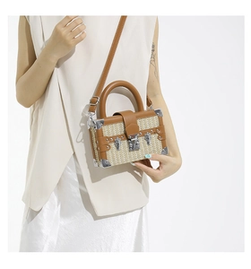 Detail of vintage straw box bag with brown leather trim and metallic lock on model