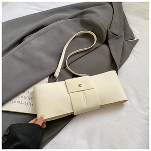 Detail of cream bow-shaped handbag showing the smooth synthetic leather and metal fastener