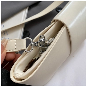 Detail of cream white leather shoulder bag featuring polished silver metal hardware and zipper