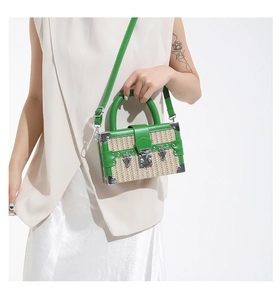 Detail of green leather edges and natural straw weave on a mini box crossbody bag