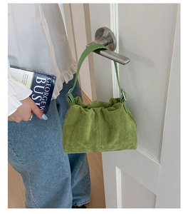 Detail of green suede pleated tote bag with adjustable metal buckle on white door
