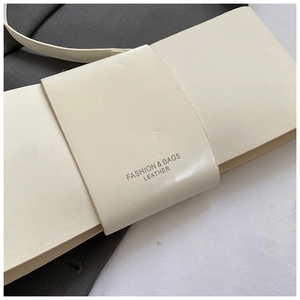 Detail of cream leather shoulder bag featuring a wide decorative buckle and fashion logo
