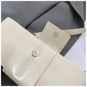 Close-up of off-white leather shoulder bag featuring a magnetic metal buckle closure