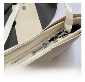 Detail of silver zipper closure and metallic buckle on cream white baguette bag