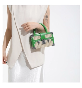 Detail of woven straw box bag in green and beige with metal clasp and vintage corners