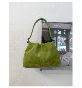 Dettaglio del materiale scamosciato verde erba e del manico in pelle liscia della borsa