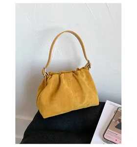 Dettaglio borsa a mano in pelle scamosciata gialla con finiture in metallo argentato