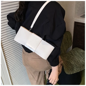 Close-up of minimalist white leather baguette bag with bow design and fashion lettering