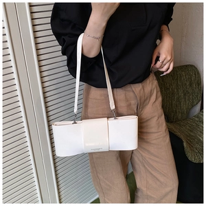 Model wearing a cream leather underarm bag with decorative FASHION & BAGS lettering