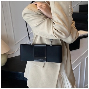 Detail of black leather baguette bag with unique wide bow design and silver lettering