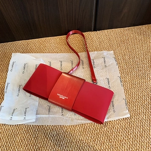 Close-up of bright red PU leather bag with metallic logo detail and thin shoulder strap