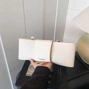 Detail of cream white leather baguette bag with bow design and silver metal buckle