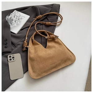 Detail of tan suede crossbody bag with elegant knot strap and silver hardware accents