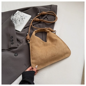 Detail of tan suede tote with V-cut handle and decorative knotted shoulder strap