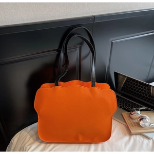 Detailaufnahme der orangefarbenen Tragetasche mit Wellenrand und Litchi-Textur