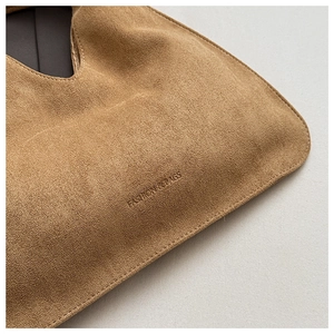Detailed close-up of brown suede fabric with FASHION&BAGS embossed logo on the bag