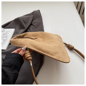 Detail of faux suede dumpling bag featuring a decorative knotted strap and silver hardware