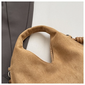 Close-up of premium camel suede handbag featuring twisted rope detail and metallic buckle