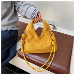 Detail of yellow suede hobo bag featuring deep V-shaped design and unique knotted strap