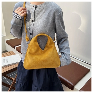 Detail of a bright yellow suede dumpling bag with slim shoulder strap and metal buckle