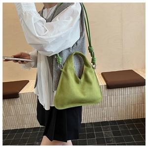 Detailed close-up of a bright green suede handbag with a unique knot and metal ring detail