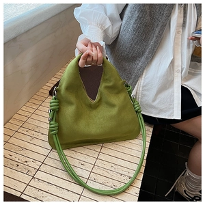 Detail of green suede dumpling bag featuring unique knot strap and soft matte texture