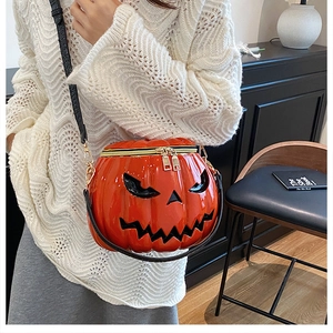 Detail of pumpkin crossbody bag with jack-o'-lantern face and gold zipper on a model