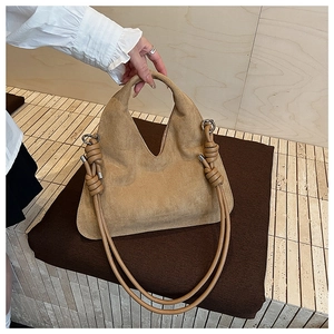 Detail of suede hobo bag featuring knotted shoulder strap and sleek silver hardware