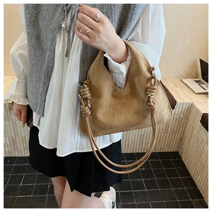 Detail of brown suede dumpling bag featuring distinctive knotted rope handle design