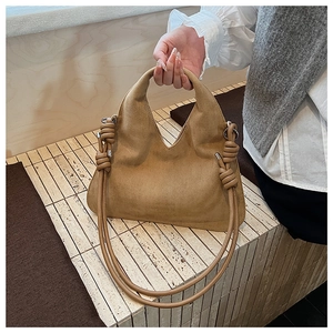 Detail of camel suede tote bag featuring a V-shaped top and rope knot shoulder strap