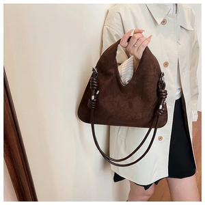 Detail of dark brown suede crescent bag featuring intricate leather braided knot and silver hardware
