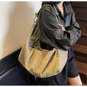 Detail of olive green pleated hobo bag with textured vertical folds and double straps