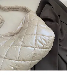 Close-up of beige quilted puffer tote bag with soft padded straps and shiny texture