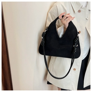 Close-up of black suede hobo bag featuring stylish leather knotted straps and silver metal clasp