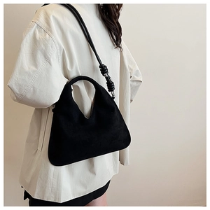 Close-up of black suede dumpling bag featuring unique knotted rope handle detail