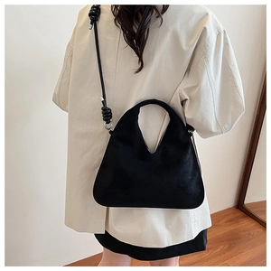 Close-up of black suede dumpling bag with V-shaped handle and knotted shoulder strap
