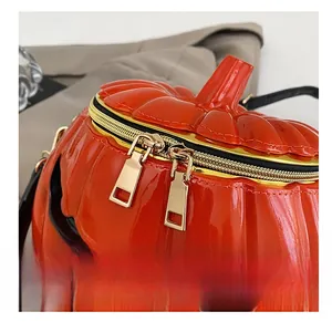 Close-up of dual gold zippers on bright orange glossy pumpkin handbag for Halloween