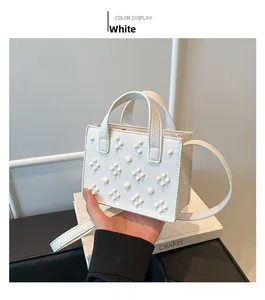 Détail du sac à main en cuir litchi blanc orné de motifs géométriques en perles blanches
