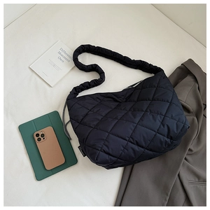Flat lay of black quilted tote bag with everyday essentials for office and travel use
