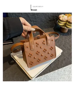 Détail du sac en cuir marron avec motif litchi, rivets décoratifs et poignées