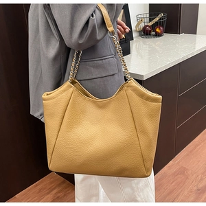 Détail d'un sac cabas jaune de grande capacité avec chaîne en argent et cuir souple