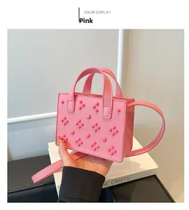 Détail du mini sac carré rose en cuir grainé avec design de rivets floraux