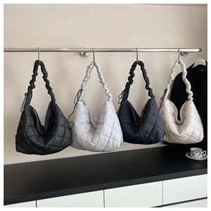 Quilted puffer tote bags in black, silver, navy, and cream hanging on a metal display rack