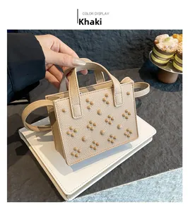 Détail d'un mini sac carré kaki avec grain litchi et rivets ronds décoratifs