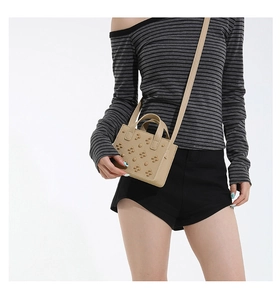 Détail d'un mini sac bandoulière marron clair avec rivets fleurs et poignée supérieure