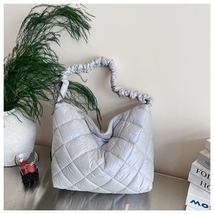 Detail of silver quilted tote bag with padded nylon texture and checkered bow charm
