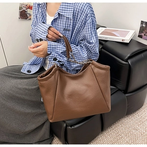 Détail du cabas marron en cuir texturé avec chaîne argentée dans un décor quotidien