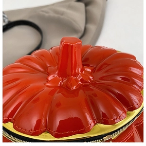 Detail view of pumpkin handbag with shiny patent texture and gold zipper closure