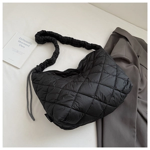 Detail of black quilted puffer tote featuring pleated wide straps and contrast drawstrings